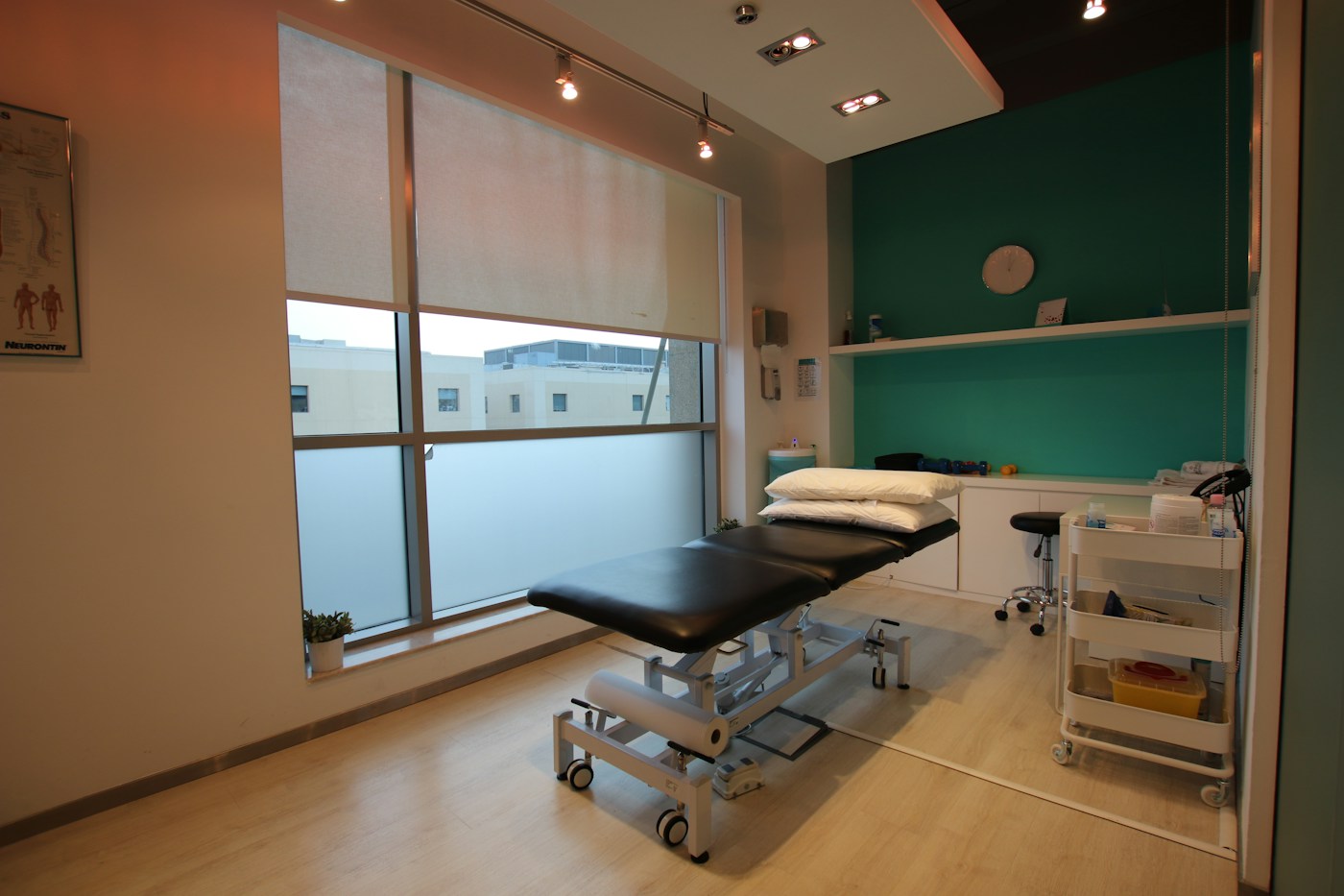 Sala de tratamiento con camilla, ventanal y material de rehabilitación